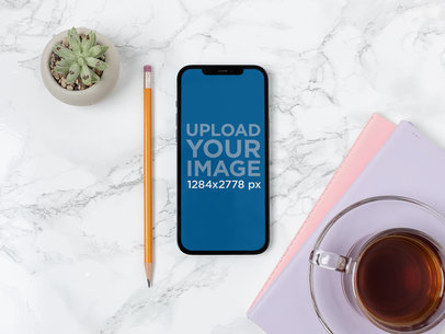 Mockup of an iPhone 12 Pro Max on a Table Next to a Hot Tea