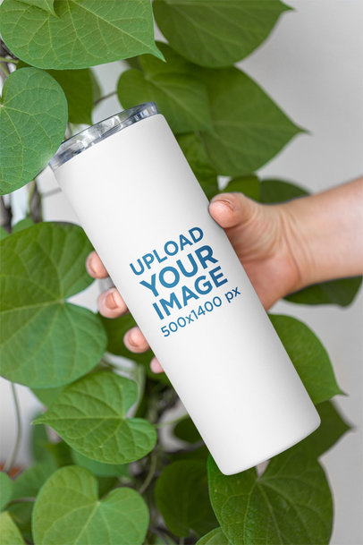 Mockup of a Skinny Tumbler Being Held by a Woman Featuring Some Leaves