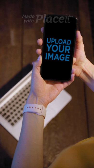 Video of a Woman Holding an iPhone 12 Pro Max Featuring a Laptop in the Background 