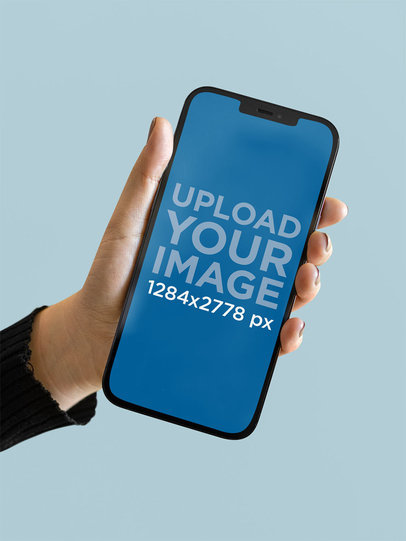 Mockup of a Woman Holding an iPhone 12 Pro Max Against a Plain Background m21955