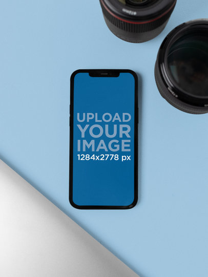 Mockup of an iPhone 12 Pro Max Facing Up Next to Professional Camera Lenses m21868