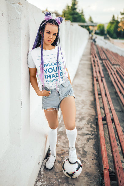 Round-Neck T-Shirt Mockup Featuring a Serious Woman Posing With a Soccer Ball