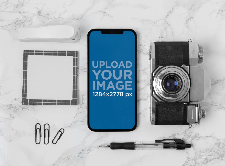 Mockup of an iPhone 12 Pro Max Placed over a Marble Surface by a Retro Camera