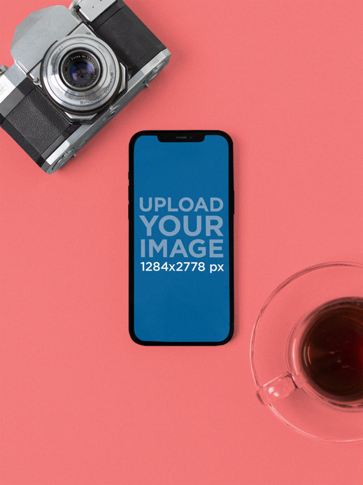 Mockup of an iPhone 12 Pro Max Placed in Portrait Position by a Vintage Camera