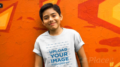 Boy Wearing a Kid's Round Neck Tee Video Standing Against a Painted Wall