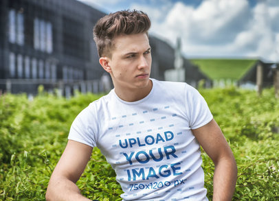 Round-Neck T-Shirt Mockup Featuring a Serious Man Posing Against a Bush