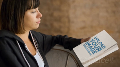 Short Haired Woman Holding a Book Video Mockup while Sitting