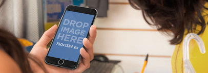Wide Mockup of a Woman Holding an iPhone 6 while Shopping