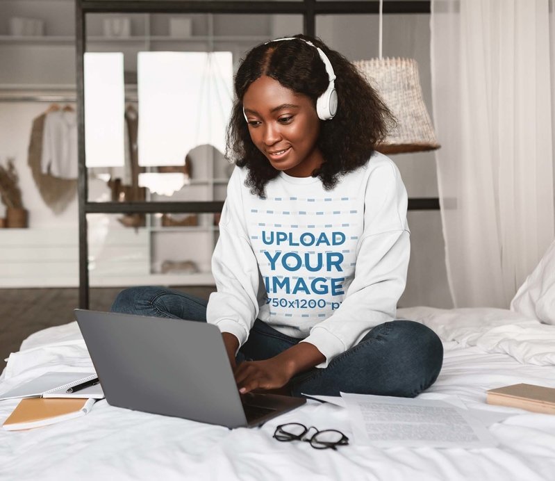 Crewneck Sweatshirt Mockup Featuring a Smiling Woman With Headphones Working on Her Laptop