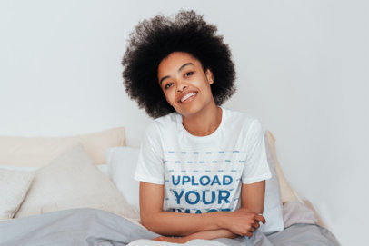 T-Shirt Mockup of a Woman with Natural Hair Sitting on Her Bed