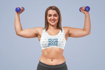 Sports Bra Mockup of a Happy Woman Holding a Pair of Dumbbells 