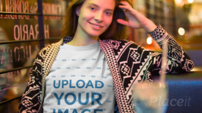 Young White Woman Wearing a T-Shirt Video Mockup at a Coffee Shop at Night