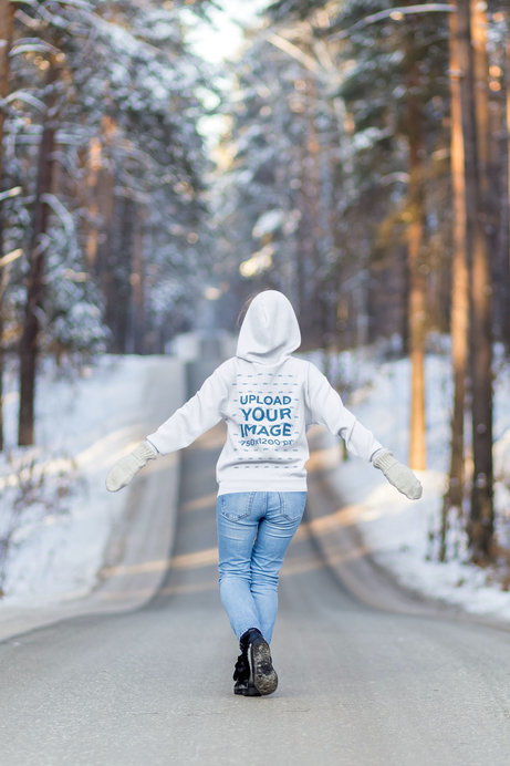 Back-View Hoodie Mockup of a Woman Walking on a Snowy Road