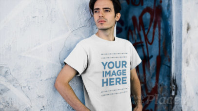 Young Man Wearing a Tshirt Video Lying Against an Old Wall