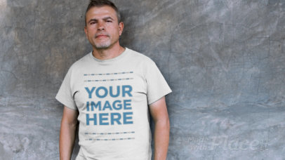 Video of a Middle Aged Hispanic Leaning Against a Black Wall Wearing a T-Shirt Mockup