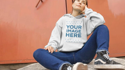 Video of a Woman Sitting Down with Legs Open Wearing a Pullover Hoodie