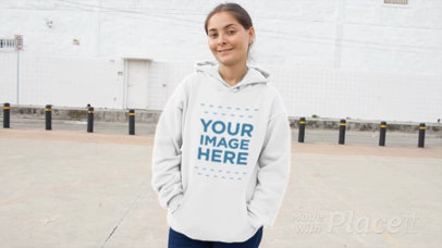 Front Shot of a Woman Wearing a Pullover Hoodie Video Mockup at an Industrial Zone