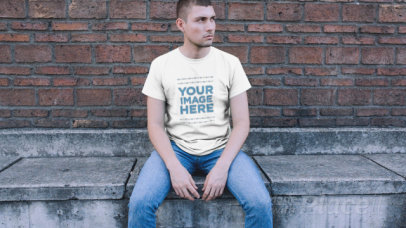 Trendy Guy Sitting in a Downtown Street Wearing a Simple Round Neck Tee Video Mockup