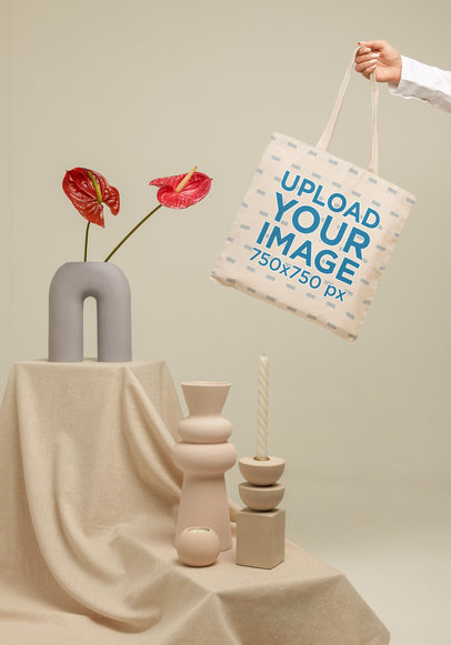 Mockup of a Woman's Hand Holding a Tote Bag Next to Some Pottery