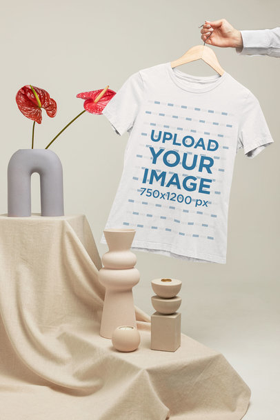 Mockup of a Woman Holding a T-Shirt on a Hanger by Some Pottery