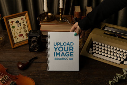 Mockup of a Woman Holding a Spiral Notebook Featuring a Dark Academia Set
