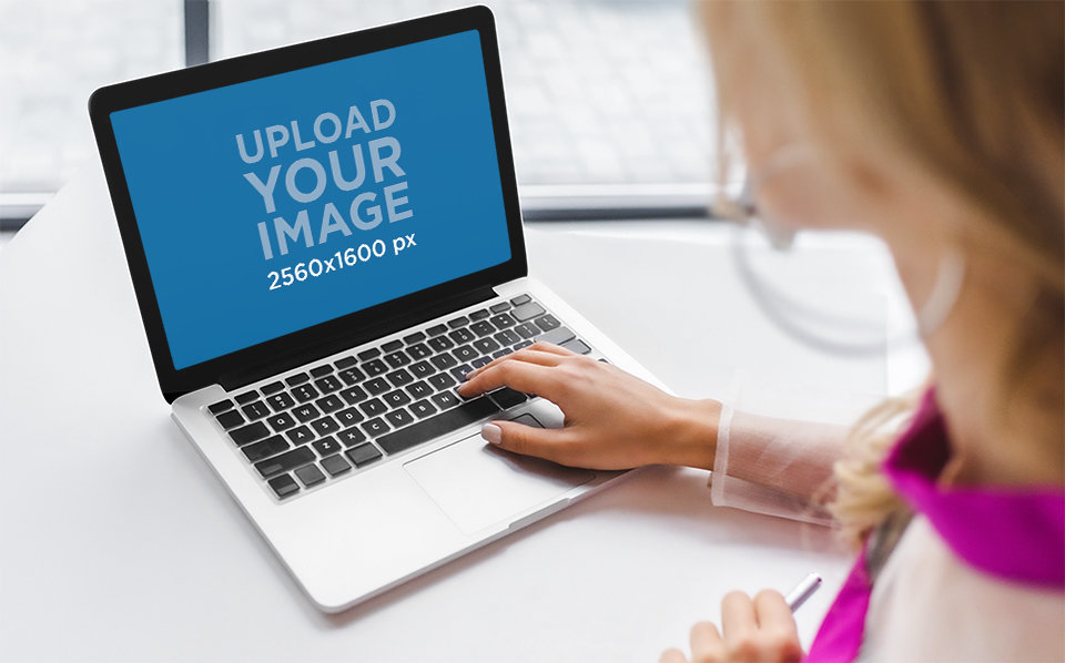 Placeit - Digital Mockup of a Woman Using a MacBook on Her Desk