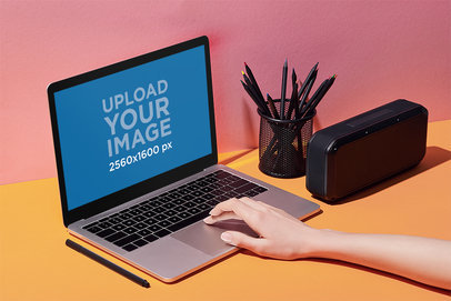 Mockup of a Woman Using a MacBook in a Colorful Workspace M14863-r-el2
