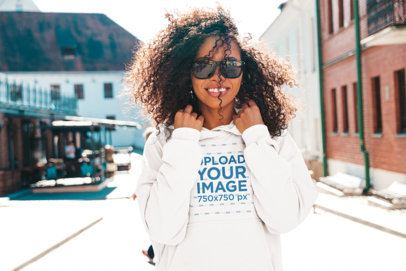 Mockup of a Kinky-Haired Woman Posing with a Hoodie in an Urban Area