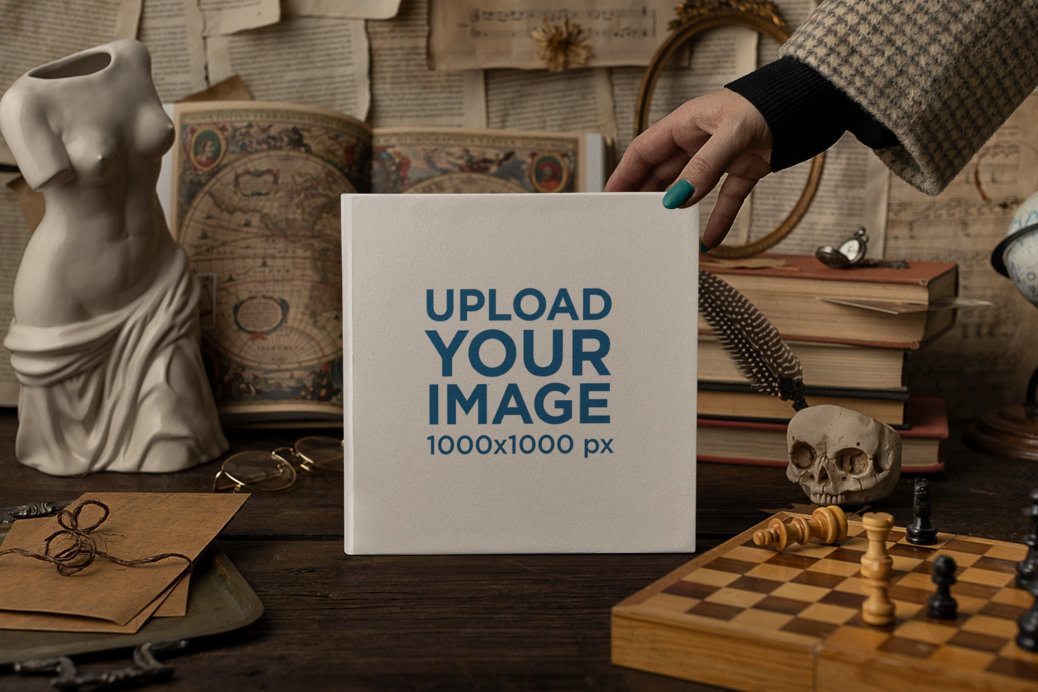 Mockup of a Woman Placing a Squared Book on a Table with Vintage Objects