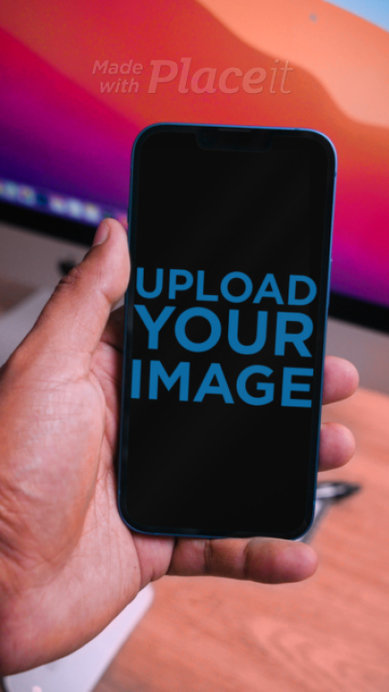 Video of a Man Holding an iPhone 13 in Portrait Position Against a Desk with an iMac