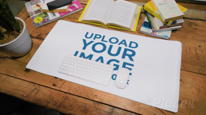 Video of a Desk Pad Placed on a Wooden Table Featuring an Open Book and a Plant