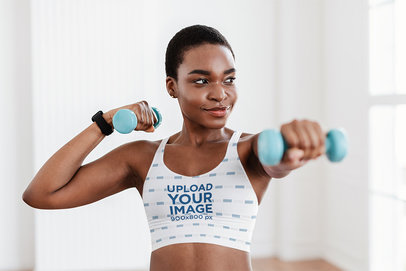 Sports Bra Mockup Featuring a Woman Exercising With Dumbbells
