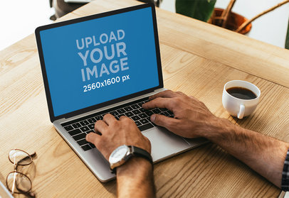 Mockup of a Man Working on His MacBook Pro While Having Coffee M16573-r-el2
