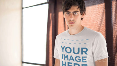 Young Guy Wearing a Short Sleeved Tshirt Cinemagraph Mockup With a Curtain Moving in the Back a13329
