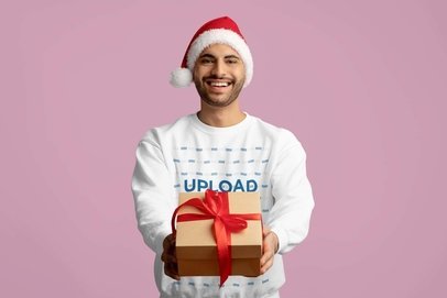 Round-Neck Sweatshirt Mockup of a Smiling Man with a Santa Claus Hat Holding a Gift