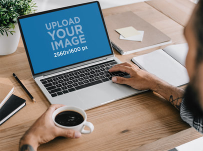 MacBook Mockup of a Tattooed Man Working on His Desk