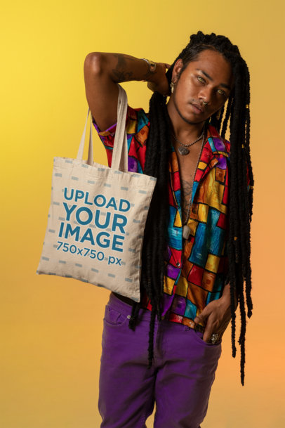 Mockup of a Tote Bag Featuring a Person with Tattoos Posing Against a Colorful Background