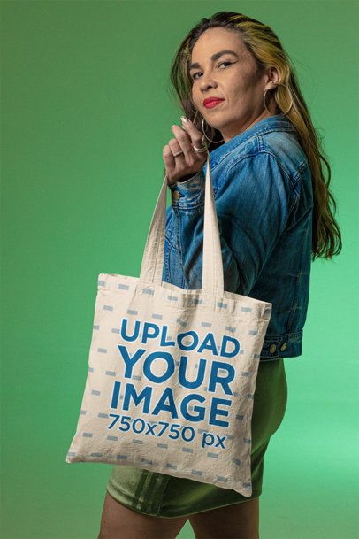 Mockup of a Woman Posing with a Sublimated Tote Bag at a Studio