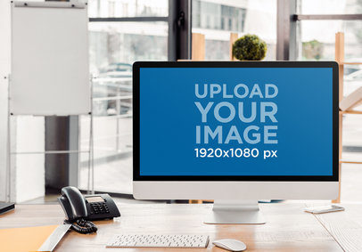 Mockup of an iMac Placed on a Wooden Desk by a Telephone
