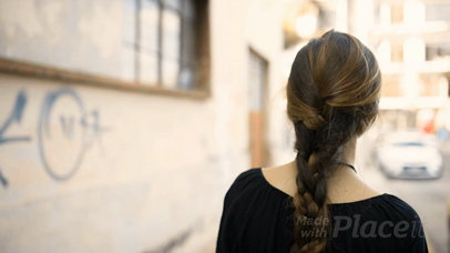 Young Woman Walking to Put a Poster Video on a Concrete Wall