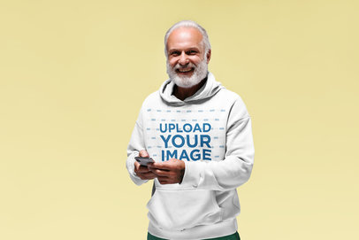 Pullover Hoodie Mockup of an Elderly Man with Beard Using a Smartphone