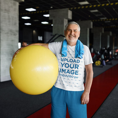 Crewneck Tee Mockup of a Smiling Senior Man Holding a Gym Ball