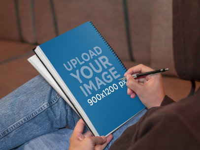 Mockup of a Man Sketching On White School Notebook