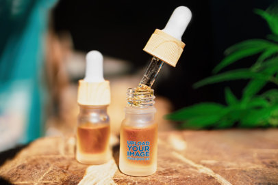 Mockup of a Dropper Bottle lying on a Wooden Surface with Cannabis in the Back