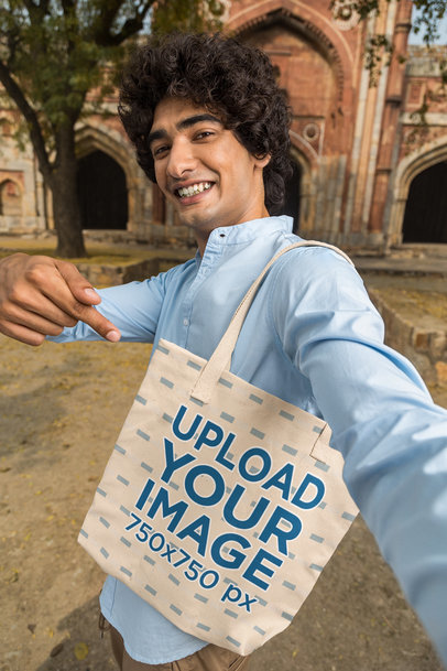 Mockup of a Young Man Pointing at a Sublimated Tote Bag