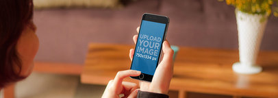 Mockup of a Woman Holding an iPhone 6 in Portrait Position