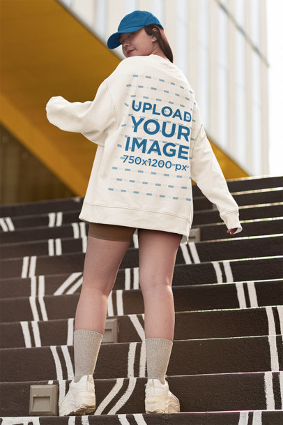 Back View Mockup of a Young Woman Wearing an Oversized Sweatshirt While Posing on a Staircase