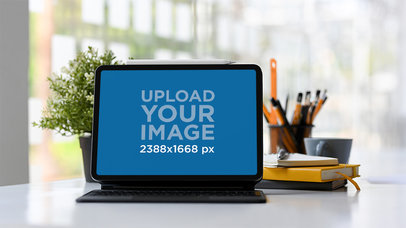 Mockup of an iPad in Landscape Position Placed Next to Some Notebooks