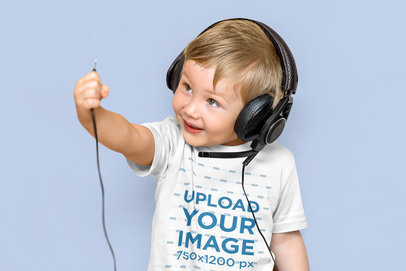 T-Shirt Mockup of a Little Boy with Headphones Against a Plain Backdrop