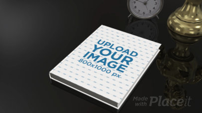 Video of a Book Lying on a Black Surface Near a Clock and a Statue